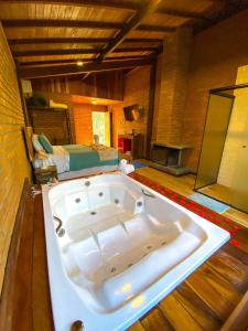 uma grande banheira branca num quarto com uma cama em Terra Verde Visconde de Mauá em Visconde de Mauá
