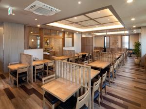 Hotel Route Inn Miyoshi Ekimae في Miyoshi: غرفة طعام مع طاولات وكراسي خشبية