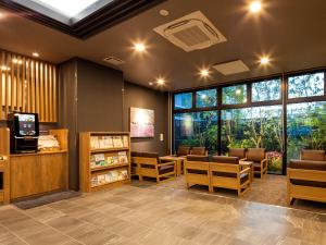 una sala de espera con sillas, mesas y ventanas en Hotel Route Inn Miyoshi Ekimae, en Miyoshi