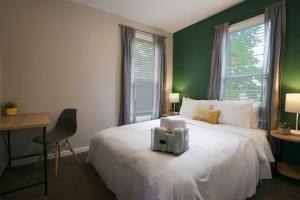 a bedroom with a white bed and green walls at Housepitality - The Lilley Pad - Near Downtown in Columbus
