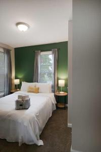 a bedroom with a white bed with a green wall at Housepitality - The Lilley Pad - Near Downtown in Columbus