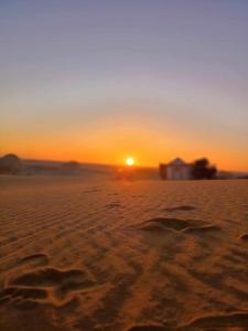 a sunset in the desert with footprints in the sand at Abo Yusre Sfari in Bawiti