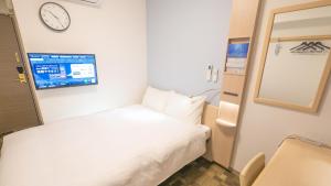 a small room with a bed and a clock on the wall at Toyoko Inn Osaka Namba in Osaka