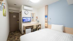 a bedroom with a bed and a desk and a tv at Toyoko Inn Osaka Namba in Osaka