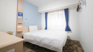 a bedroom with a white bed and a window at Toyoko Inn Osaka Namba in Osaka
