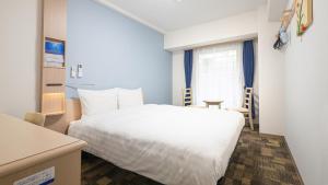 a bedroom with a white bed and a window at Toyoko Inn Osaka Namba in Osaka