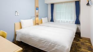 two beds in a room with a window at Toyoko Inn Osaka Namba in Osaka