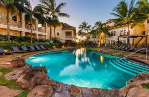 a pool at a resort with chairs and palm trees at E111 Ground Floor Poolside Patio in Koloa
