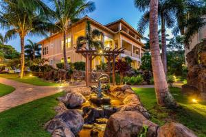 a house with a fountain in front of a yard at E111 Ground Floor Poolside Patio in Koloa