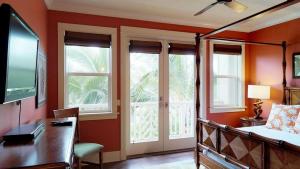 a bedroom with a bed and a desk and windows at D210 Second Floor 3-bedroom Poolside Lanai in Koloa