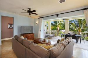 a living room with a couch and a television and a table at D211 Second Floor 3-bedroom Poolside Lanai in Koloa