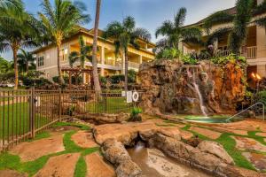 a waterfall in front of a building with palm trees at F211 Second Floor 3-bedroom Poolside Lanai in Koloa