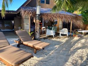 Rangiroa Sunny House في أفاتورو: مجموعة من الكراسي والطاولات على الشاطئ