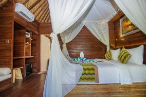 a bedroom with a bed with a canopy at The Parnas in Nusa Lembongan