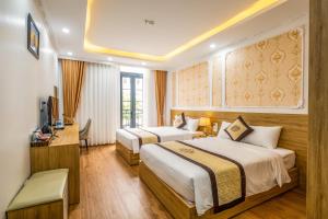 a hotel room with two beds and a desk at Thành Đô Hotel Hạ Long in Ha Long