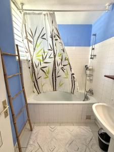 een badkamer met een douchegordijn in een bad bij Le refuge de Chrystel : Plage accessible à pied in Le Gosier