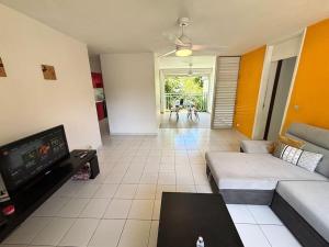 een woonkamer met een bank en een flatscreen-tv bij Le refuge de Chrystel : Plage accessible à pied in Le Gosier