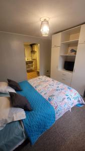 Schlafzimmer mit einem großen Bett mit blauer Decke in der Unterkunft Apartamento Estocolmo I in Valdivia