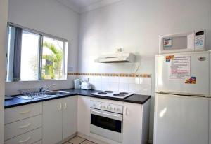 uma cozinha com electrodomésticos brancos e um frigorífico branco em Breakaway - Resort-style studio in Agnes Water em Agnes Water