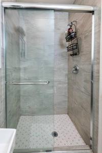 La salle de bains est pourvue d'une douche avec une porte en verre. dans l'établissement Chic and Spacious 3BR Gem in Central LA, à Los Angeles