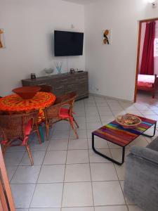 een woonkamer met een tafel en een televisie bij Pagerie bas de villa in Les Trois-Îlets