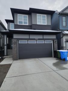 a house with a garage door and a driveway at Trendy 2-Bed Oasis Awaits! in Calgary