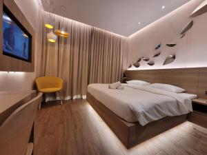 a bedroom with a large bed and a yellow chair at Wink Hotel @ Bugis in Singapore
