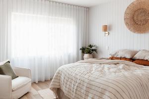 ein weißes Schlafzimmer mit einem Bett und einem Stuhl in der Unterkunft Antalya Beach House in Bridport