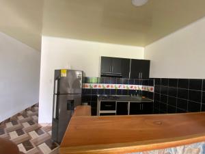una cocina con nevera de acero inoxidable y armarios negros en Apartamento bustos en Puerto Triunfo