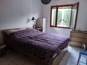 um quarto com uma cama com um edredão roxo e uma janela em Villa Saint-André, 3 pièces, 6 personnes - FR-1-776-89 em Saint-André