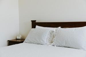 a bed with white pillows and a clock on a table at Spacious Stay On Shamrock, Bendigo in Golden Square