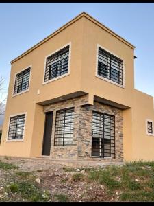 une maison avec quatre fenêtres au sommet d'une colline dans l'établissement Las Pirquitas Villa Giardino, à Huerta Grande