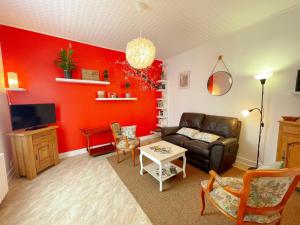 a living room with red walls and a leather couch at Gîte Loches, 3 pièces, 3 personnes - FR-1-381-572 in Loches