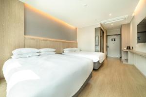 two beds in a hotel room with white sheets at Jeju Bolton Hotel in Jeju