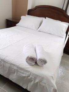 - 2 serviettes sur un lit avec des draps et des oreillers blancs dans l'établissement Encantadora Casa, Calima Darién, à Darién