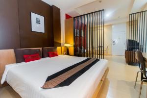 a bedroom with a large white bed with red pillows at Silom Convent Garden in Bangkok