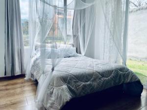 1 dormitorio con 1 cama con cortinas y ventana en ¡Fogata y Lujo! en Ambato