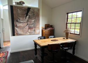 a dining room table with chairs and a painting on the wall at The Hay Shed in Mitchells Island