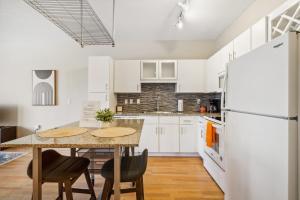 a kitchen with white cabinets and a table with chairs at CozySuites Mill District with pool, gym #01 in Minneapolis