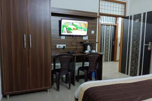 ein Hotelzimmer mit einem Schreibtisch mit Stühlen und einem TV in der Unterkunft FabHotel Divine in Gurgaon