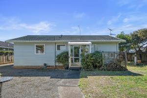 uma pequena casa branca com uma cerca num quintal em Olive Terrace - Paraparaumu Holiday Home em Paraparaumu