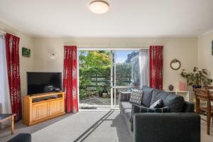 uma sala de estar com televisão e cortinas vermelhas em Olive Terrace - Paraparaumu Holiday Home em Paraparaumu