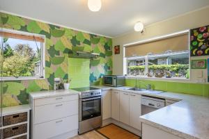 uma cozinha com armários brancos e azulejos verdes em Olive Terrace - Paraparaumu Holiday Home em Paraparaumu