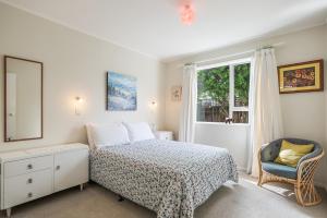 um quarto com uma cama, uma janela e uma cadeira em Olive Terrace - Paraparaumu Holiday Home em Paraparaumu