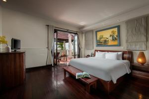 una camera da letto con un grande letto bianco e una televisione di Son Tra Resort & Spa Danang a Da Nang