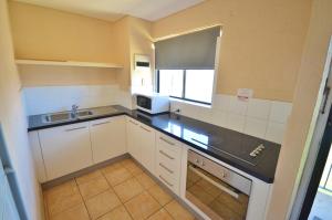 a small kitchen with white cabinets and a sink at Riverview Holiday Apartment 26 - Kalbarri WA in Kalbarri
