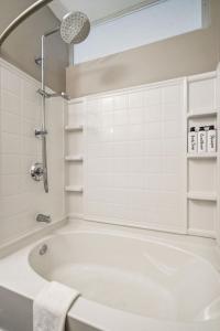 een witte badkamer met een bad en een douche bij CozySuites Mill District pool gym # 07 in Minneapolis