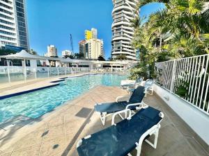 a swimming pool with two lounge chairs and a building at French provincial style, Phoenician Broadbeach in Gold Coast