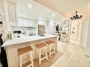 a kitchen with white cabinets and a kitchen island with stools at French provincial style, Phoenician Broadbeach in Gold Coast