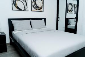Un dormitorio con una cama blanca y algunas fotos en la pared en “Hermoso Apartamento En Bávaro” en Punta Cana